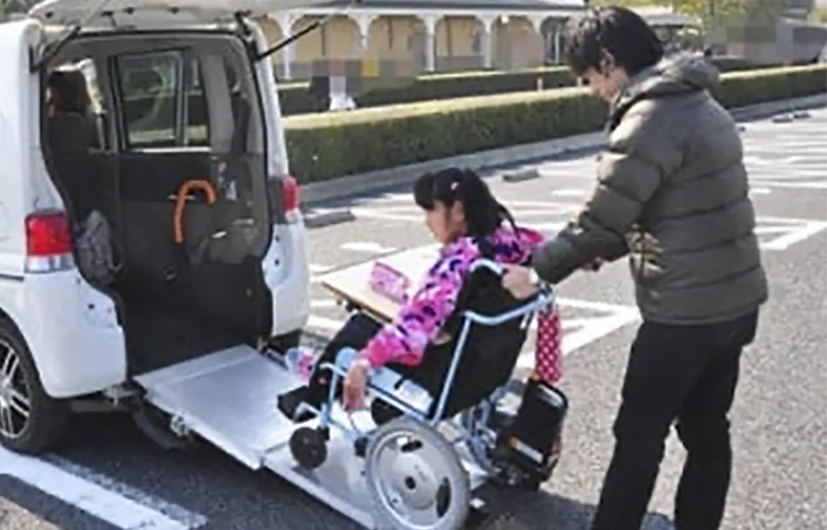 自動車に車椅子を乗せる男性スタッフの写真